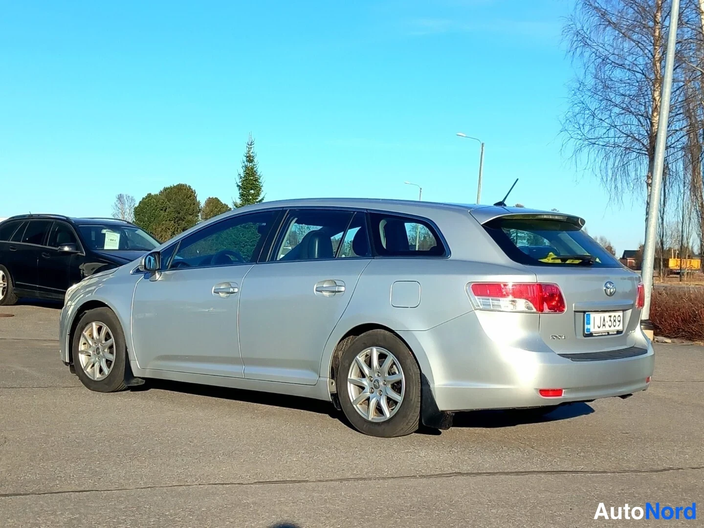 Takaviisto: Hopeanharmaa farmariauto takaviistokuva oikealta; rekisterikilpi JA-389 näkyy takaluukulla.