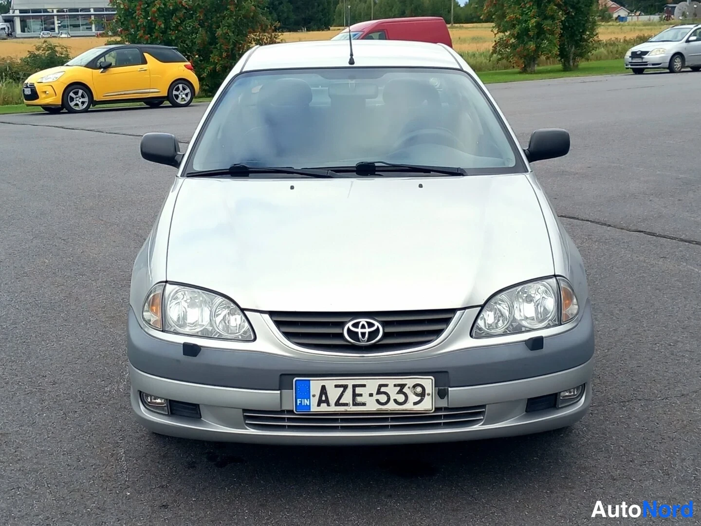 Edestä: Toyota Avensisin hopeanvärinen etupää kohtisuoraan edestä päin, rekisterikilpi.