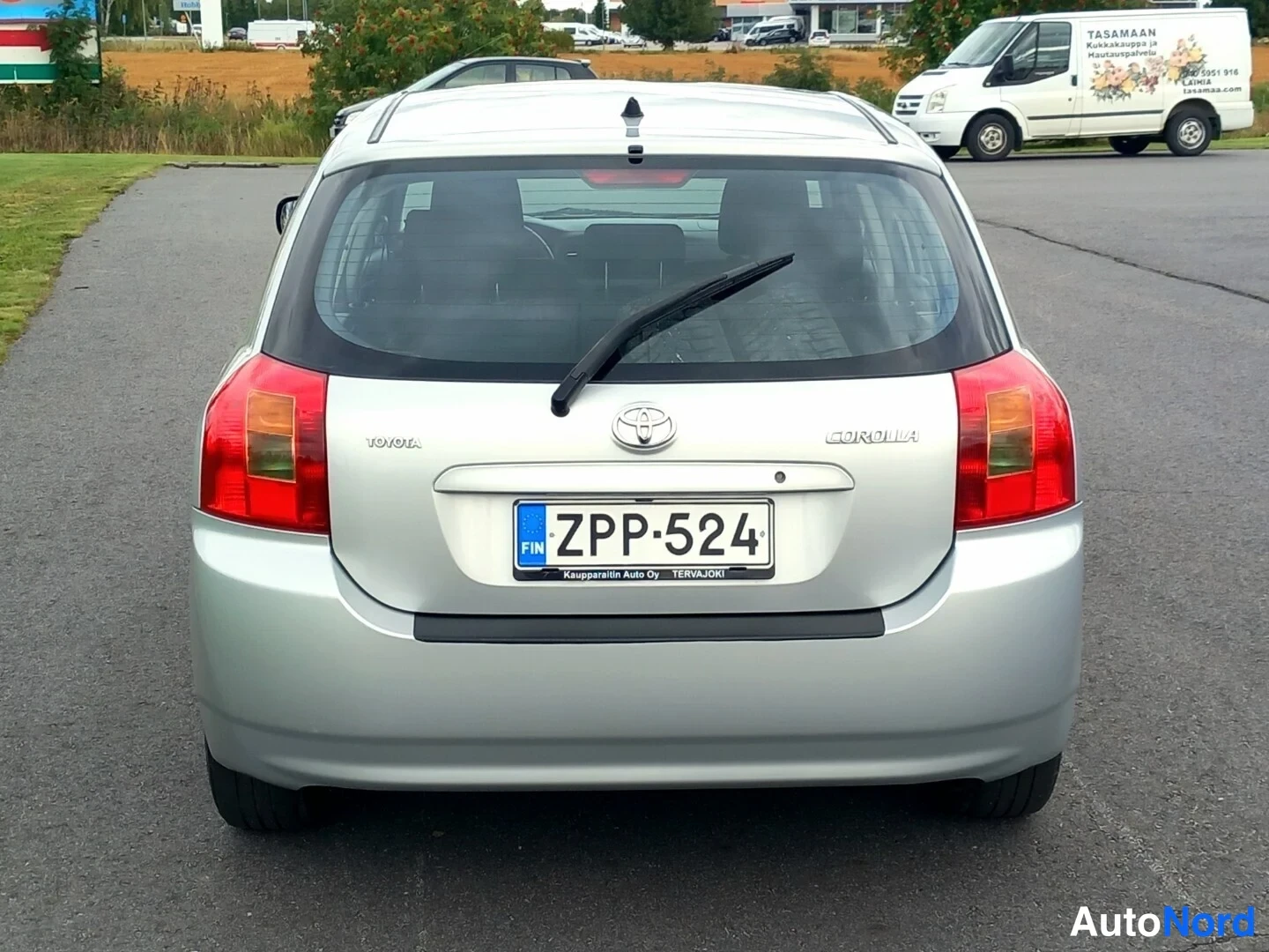 Takaa: Hopeanharmaan hatchbackin takaosa, rekisterikilpi, TÖYÖTA- ja COROLLA-merkit takaluukussa.