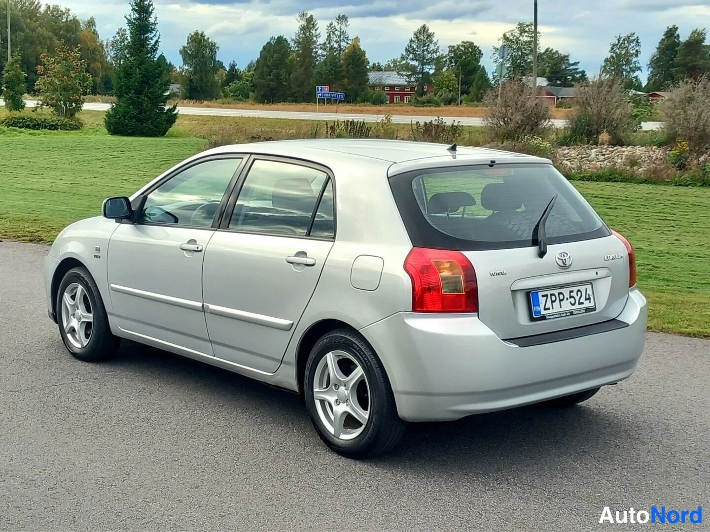 Takaviisto: Hopeanvärinen Toyota Corolla viistosti takaa vasemmalta, takatunnus, takaistuimia näkyy lasin läpi.