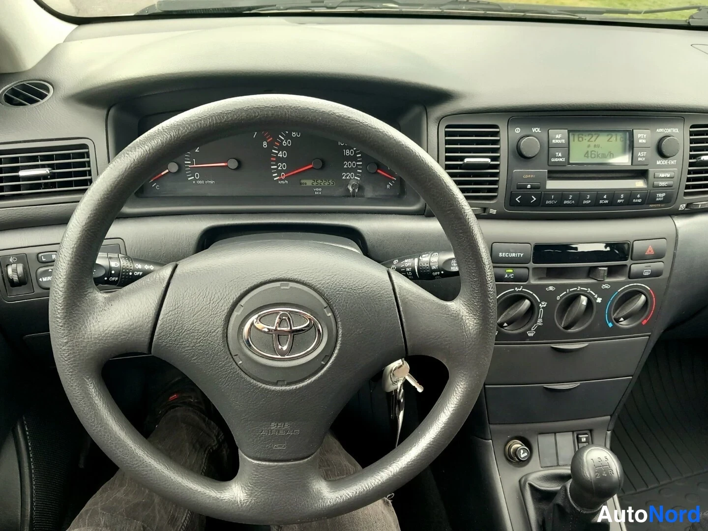 Yksityiskohta: Ohjauspyörä ja kojetaulu Toyotassa: mittaristo, radio ja A/C-nappi näkyvät.