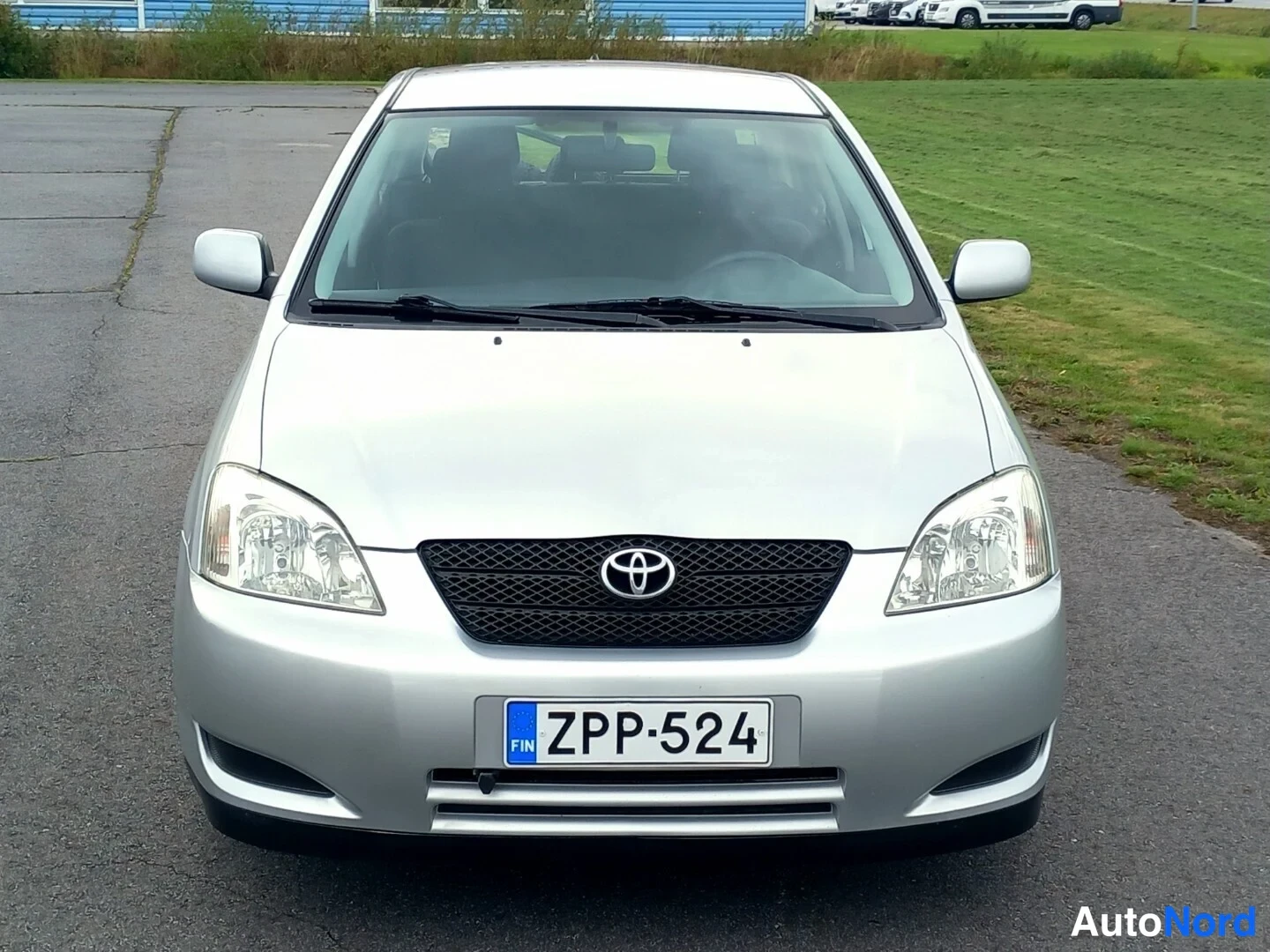 Edestä: Etukuva hopeanvärisestä Toyota Corollasta, rekisteritunnuksen oikealla.