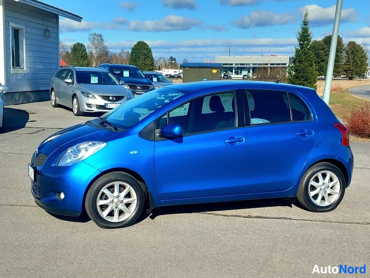 Sivulta: Sininen Toyota Yaris -henkilöauto kuvattu kulmasta edestä vasemmalta, tummat ikkulakit ja hopeavanteet.