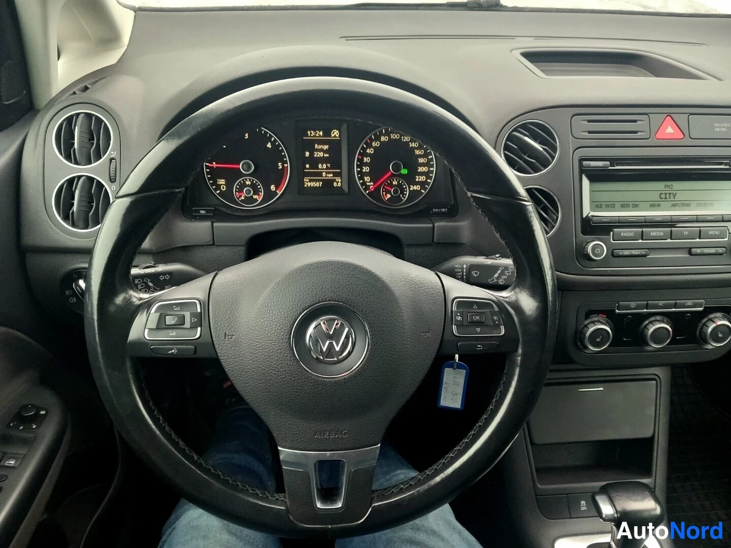 Muu: Ohjaamon näkymä Volkswagenin ratin ja mittariston yli: kilometrilukema 296507 km näkyy näytössä, radio näyttää tekstiä CITY.