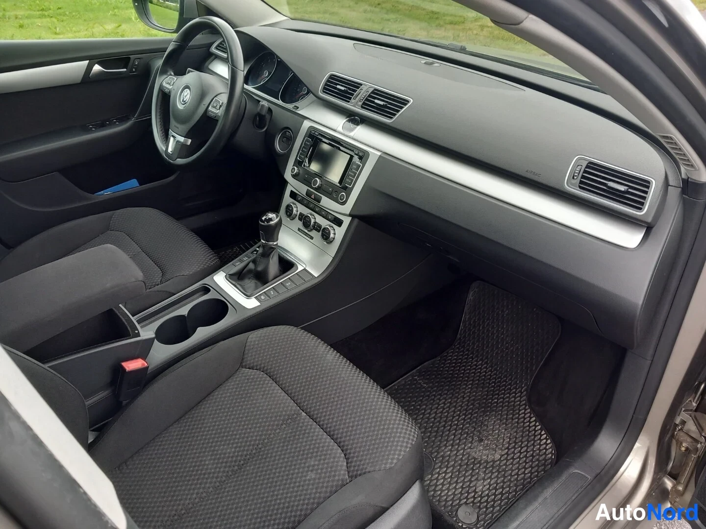 Muu: Sisäkuva autosta: tumma kangasverhoiltu ohjaamo, Volkswagen-ohjauspyörä, keskikonsolissa kosketusnäytöllinen radio, manuaali- tai automaattivaihdevipu ja käsija