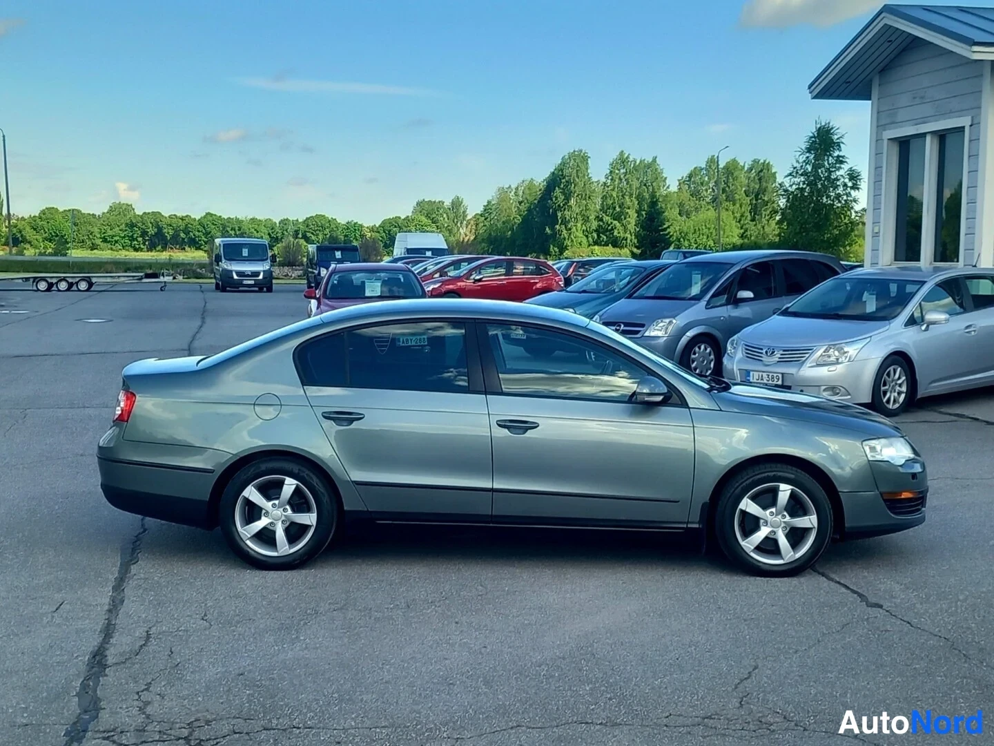 Etuviisto, nokka oikealle: Harmaanvihreä Volkswagen Passat -sedan kuvattu sivusuunnassa, keula kuvan oikeassa reunassa.