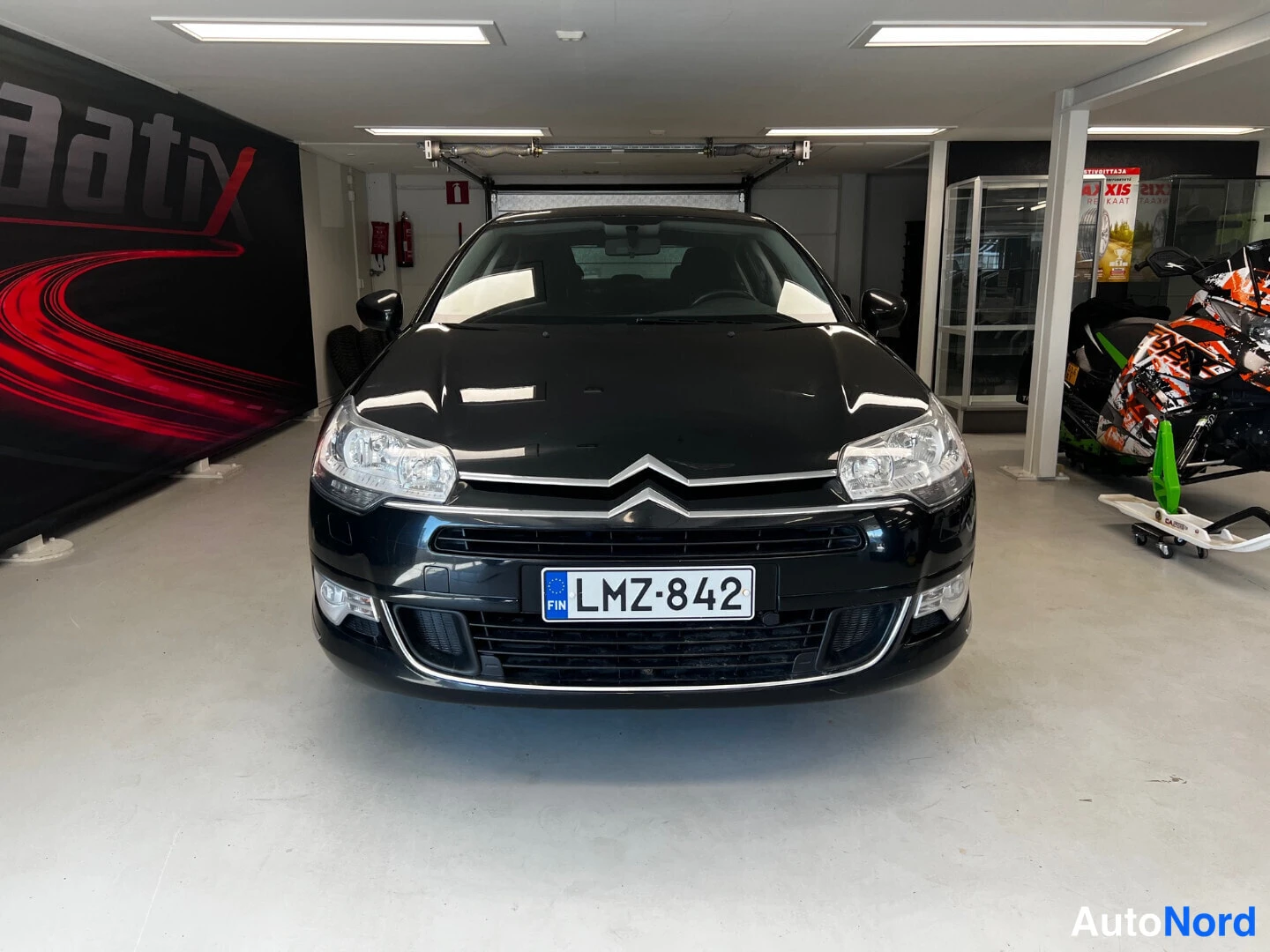 Edestä: Citroënin etusävy musta, rekisterikilpi, kuvattu suoraan edestä autotallissa.