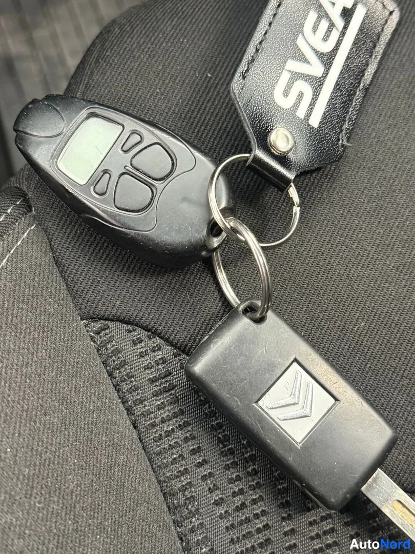 Yksityiskohta: Citroën-autoavain ja avainlukko sekä musta avainnauha, johon on painettu teksti SVEA.