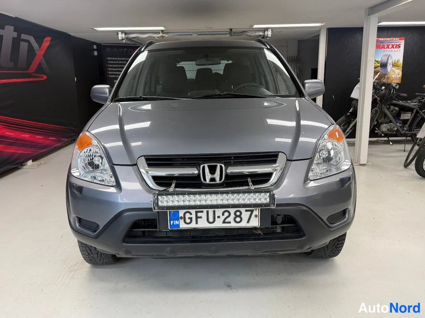 Edestä: Harmaa Honda CR-V edestä, grillissä Honda-merkki ja etupuskurissa LED-valopalkki, rekisteri.