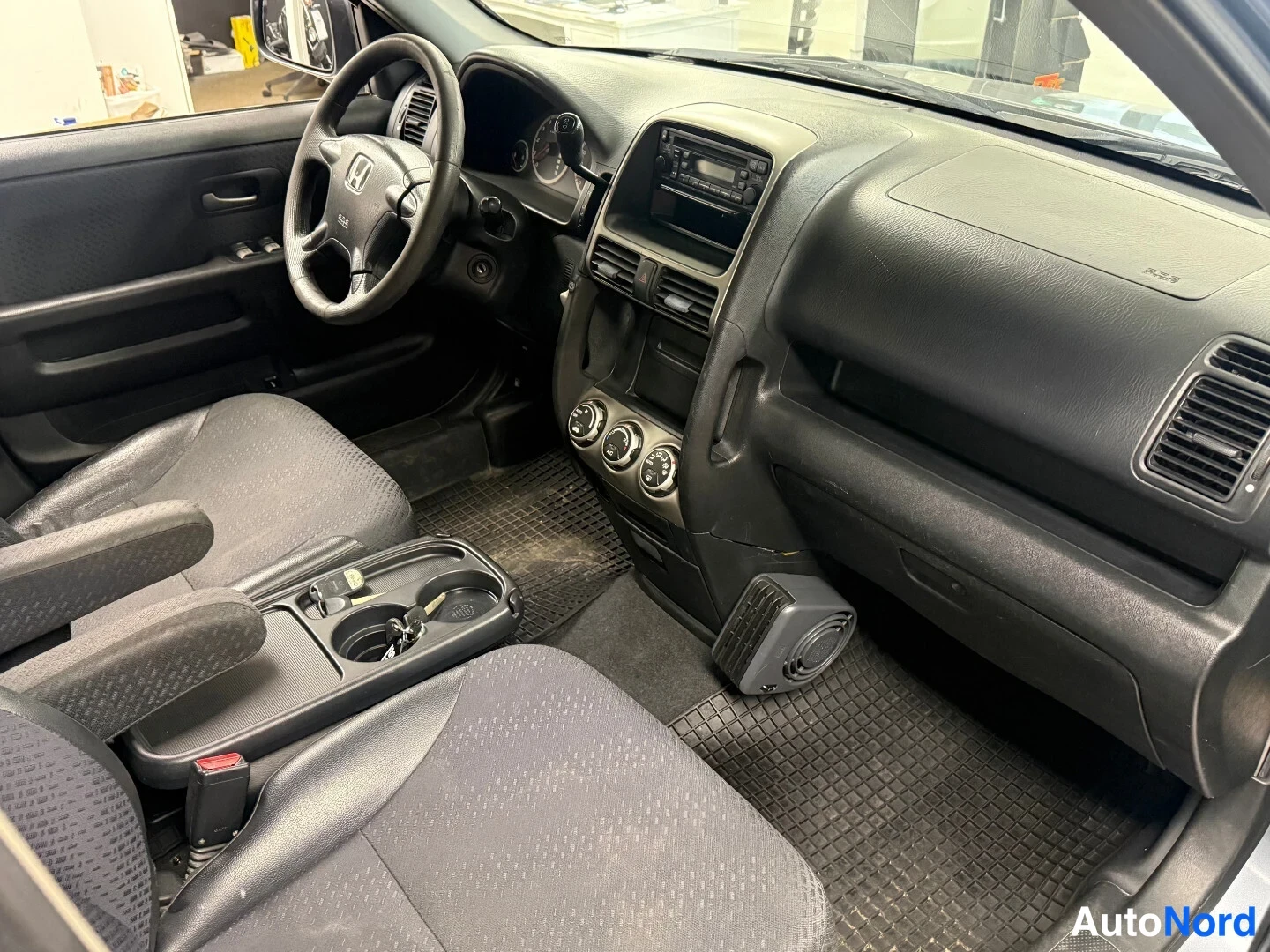 Muu: Honda CR-V:n sisätilat oikealta puolelta: tumma kojelauta, keskikonsolin radiot ja ilmastoinnin säätimet, kangasistuimet ja kumimatot.