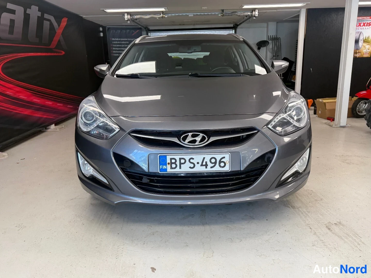 Edestä: Hyundai i40 -farmarin etupää harmaana sisätilassa, rekisterikilpi.