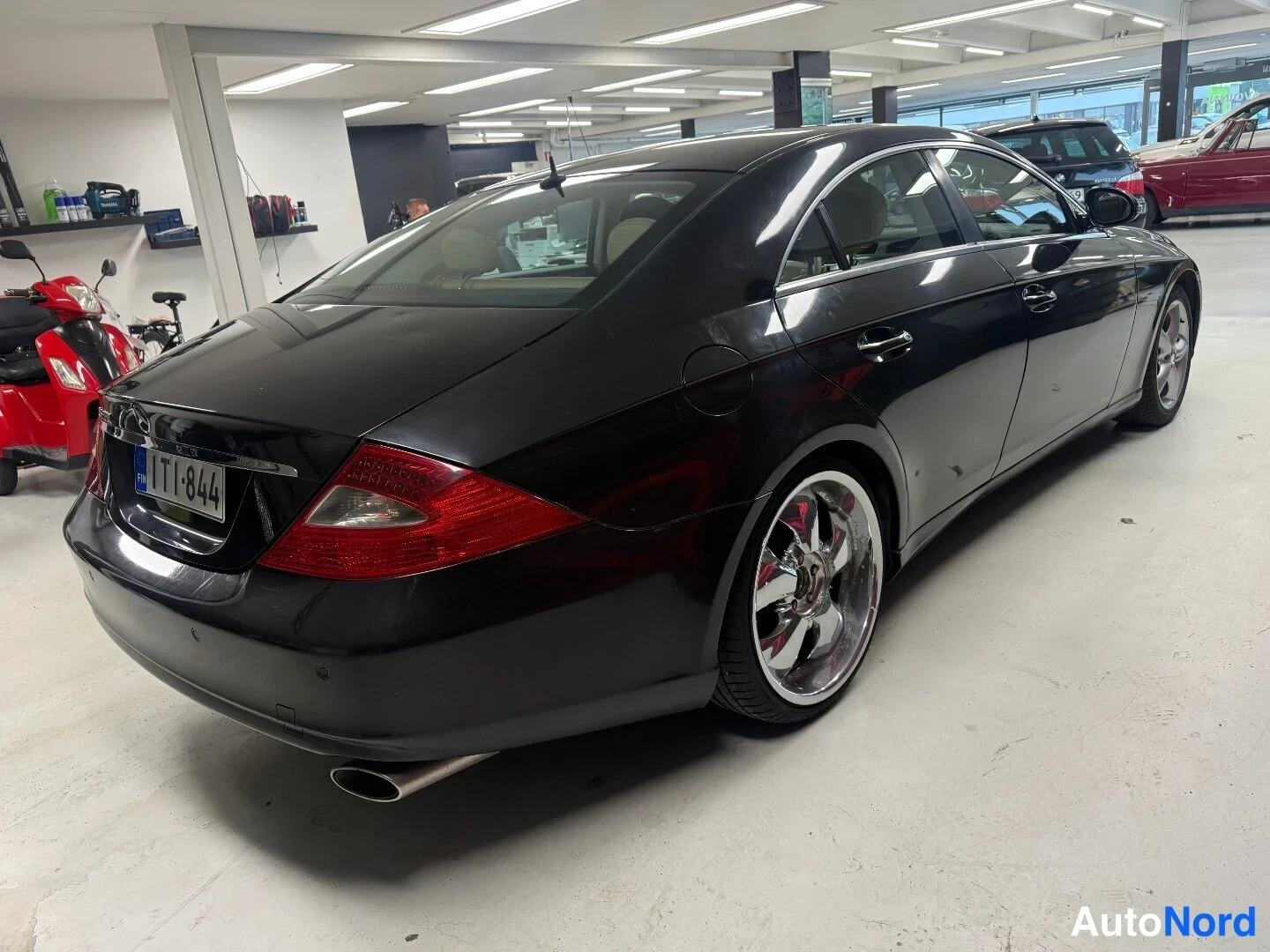 Takaviisto: Musta Mercedes-Benz CLS 350 takakulma sisätilassa, rekisterikilpi, Chrome-vanteet.