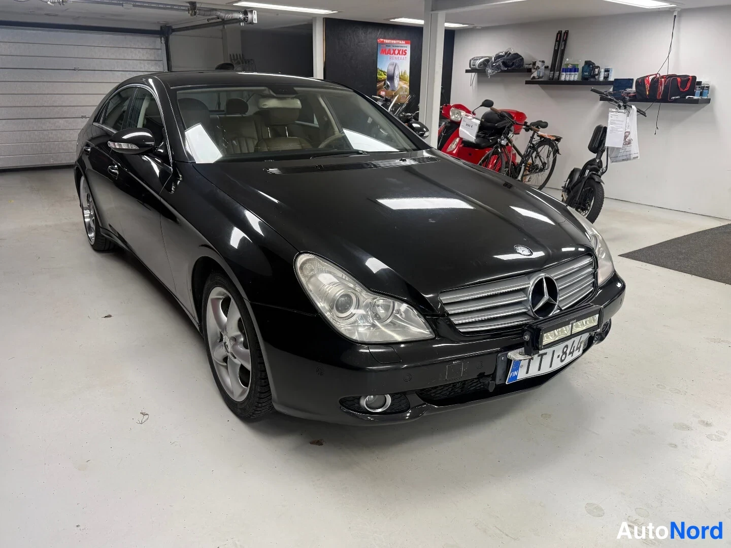 Etuviisto, nokka oikealle: Musta Mercedes-Benz CLS 350 etukulma, rekisterikilpi, konepellillä tumma kiiltävä maali.