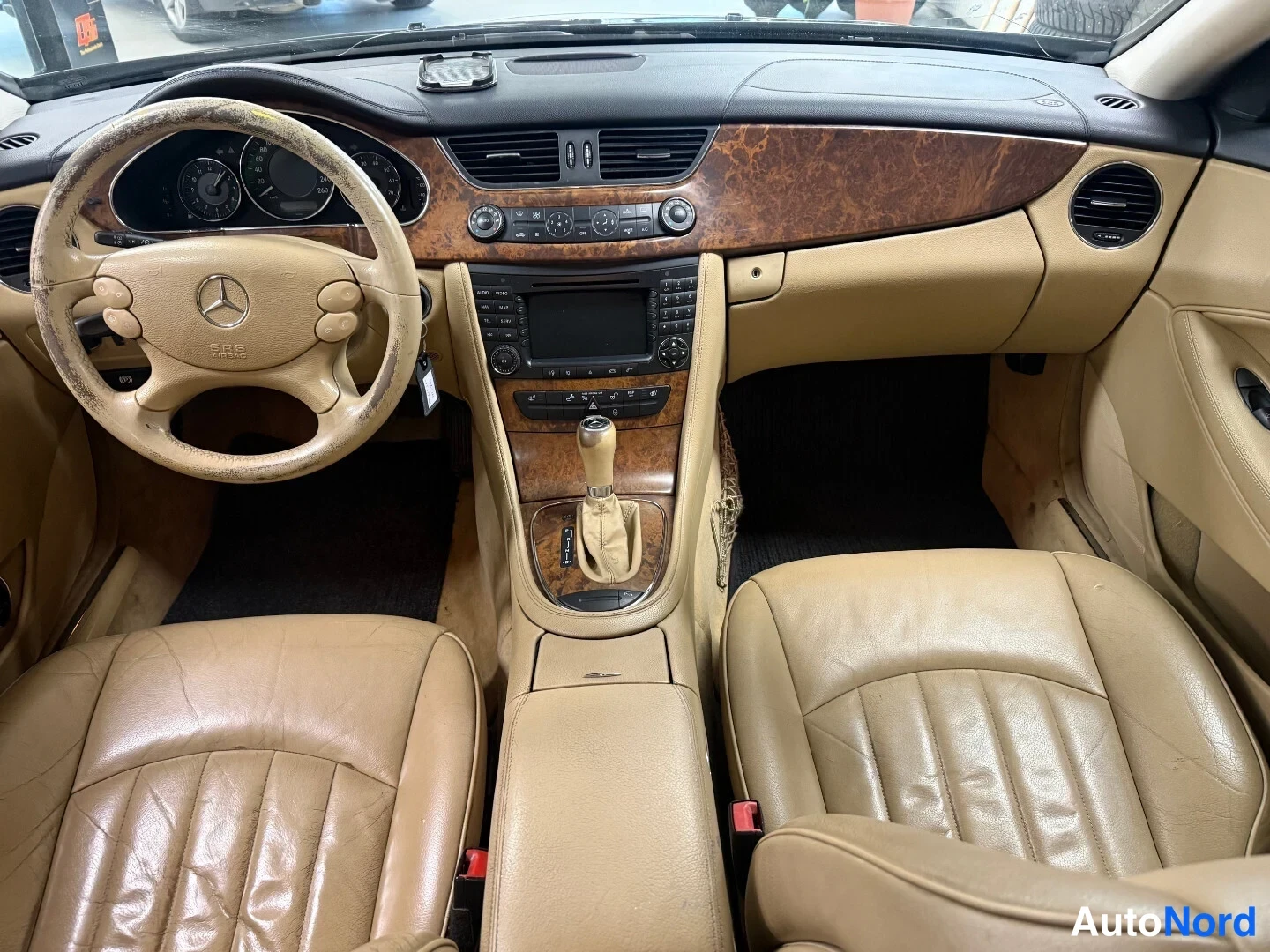 Yksityiskohta: Sisätilat: beige Nahkapenkit, puukoristeinen kojelauta ja Mercedes-ohjauspyörä.