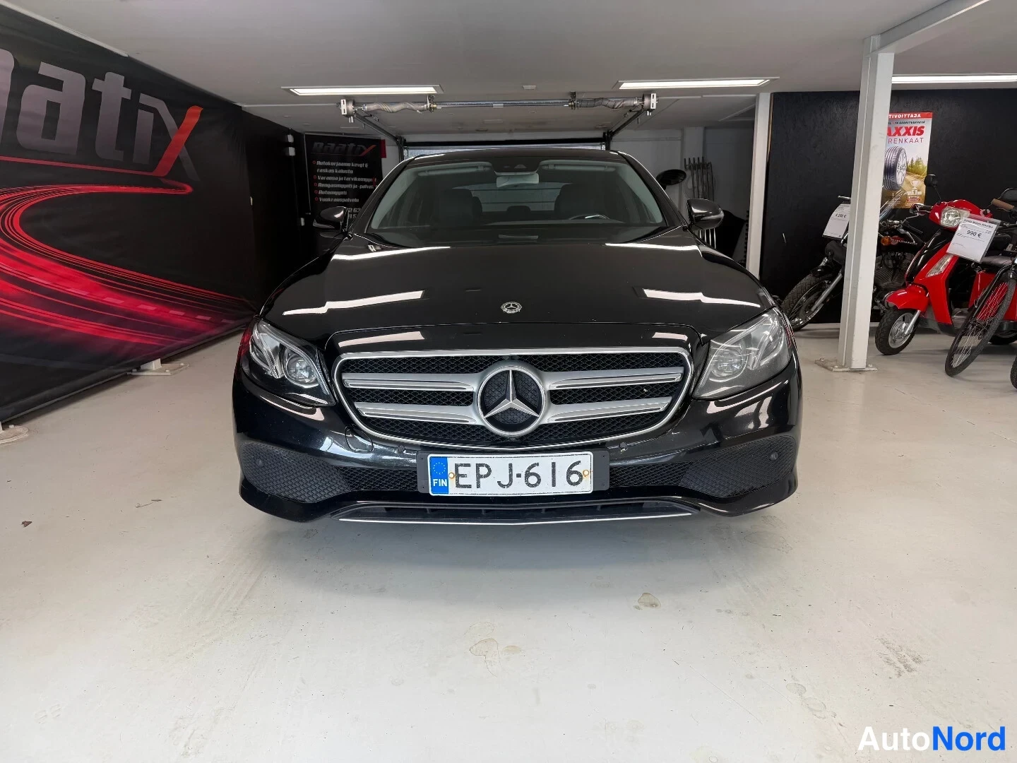 Edestä: Mercedes-Benzin etusivunäkymä musta sedan rekisteritunnus sisätiloissa.