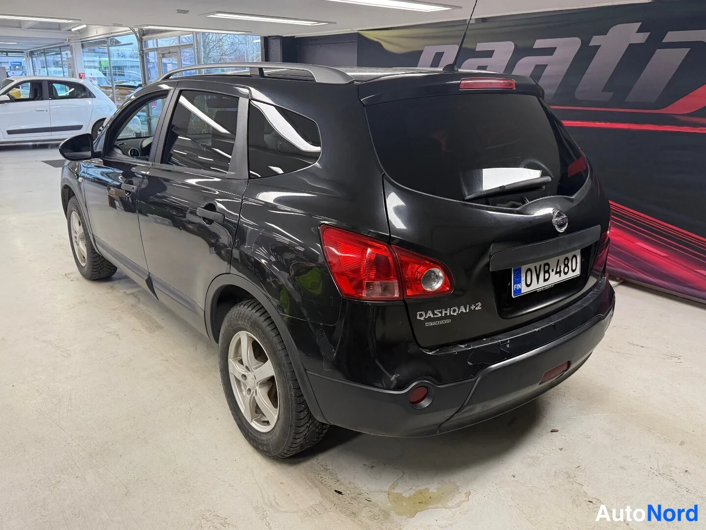 Takaviisto: Mustan Nissan Qashqai+2:n takakulmanäkymä, takaluukussa OASHQAI+2-teksti ja rekisterikilpi.