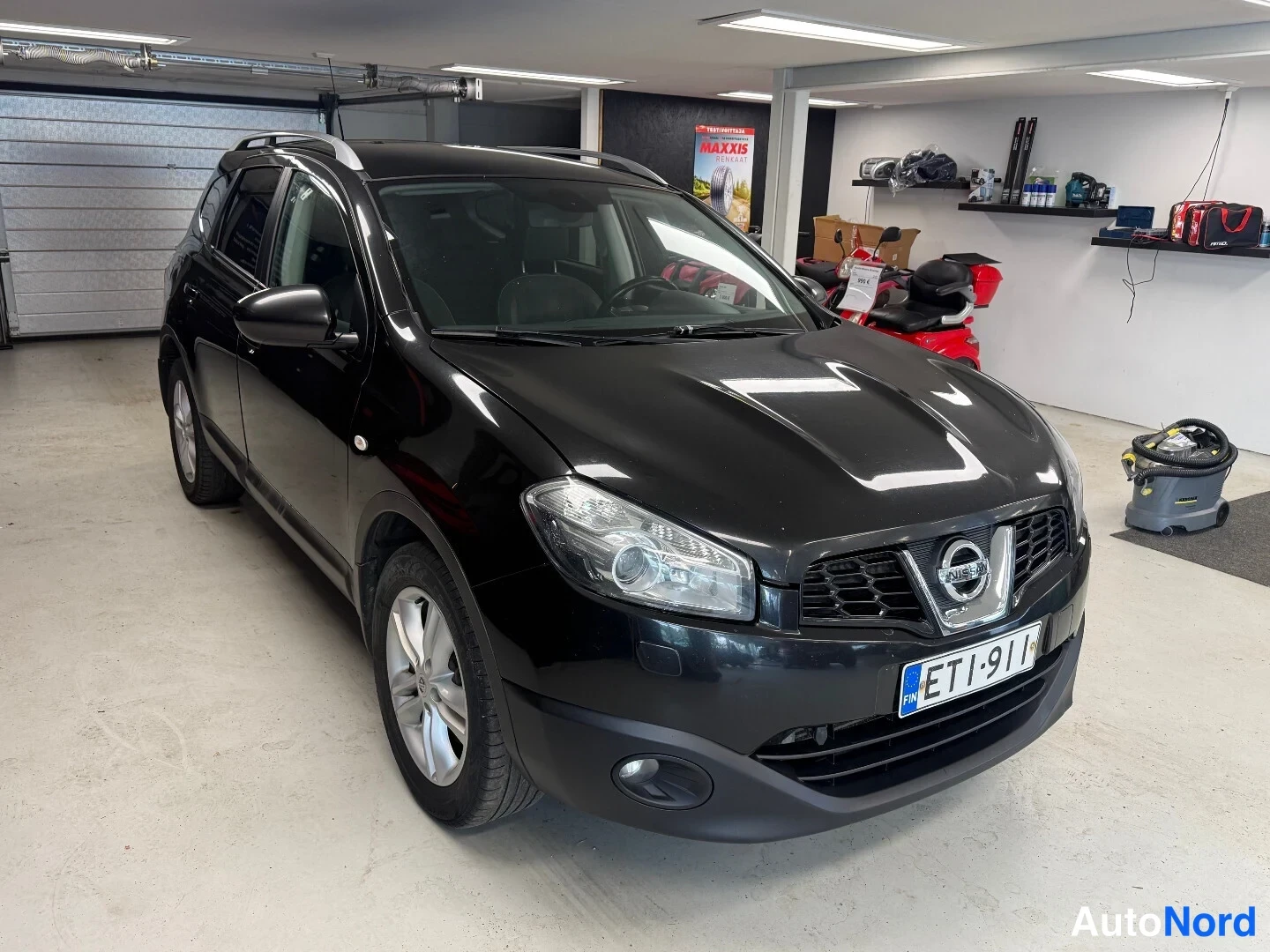 Etuviisto, nokka oikealle: Nissan Qashqai+2 etukulmasta oikealta, musta, rekisteri, katolla kattokaiteet.
