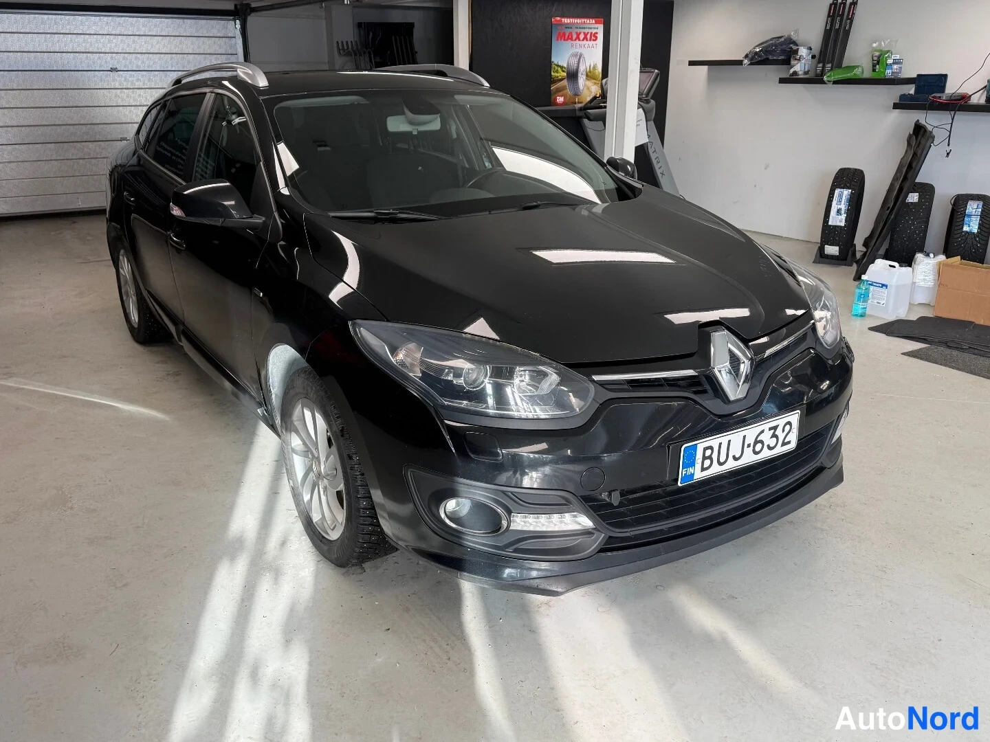Etuviisto, nokka oikealle: Mustan farmariauton etunurkka ja vasen kylki kuvattuna garagesisällä.