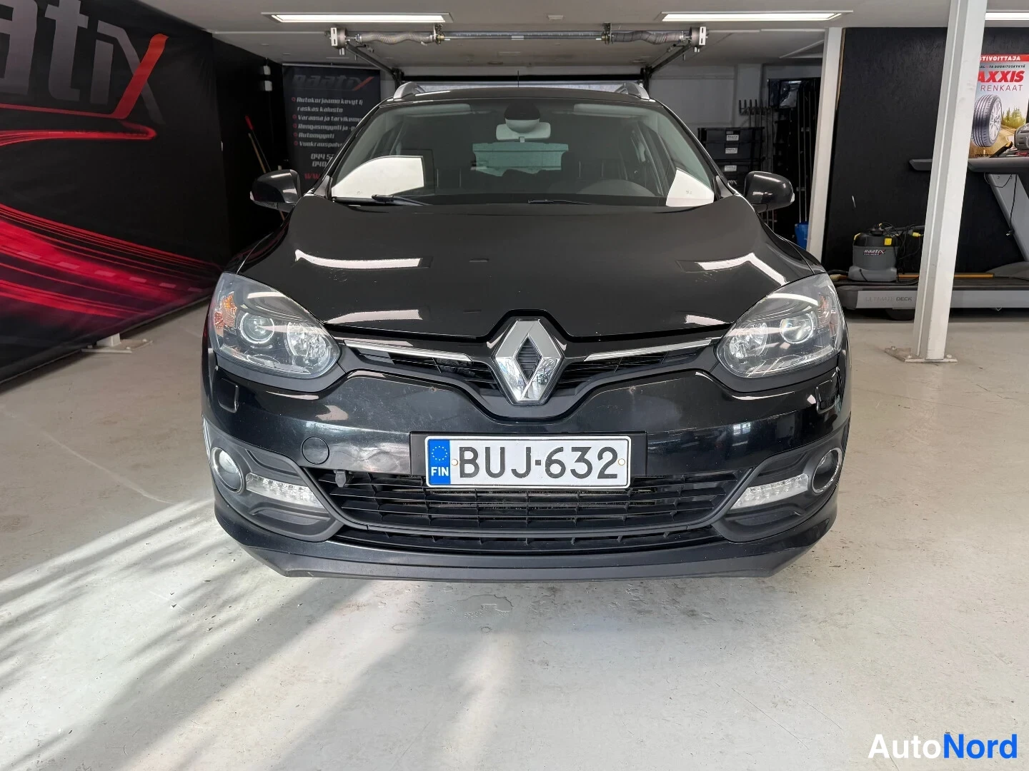 Edestä: Renaultin mustan farmariauton etupää edestä päin, rekisterikilpi.