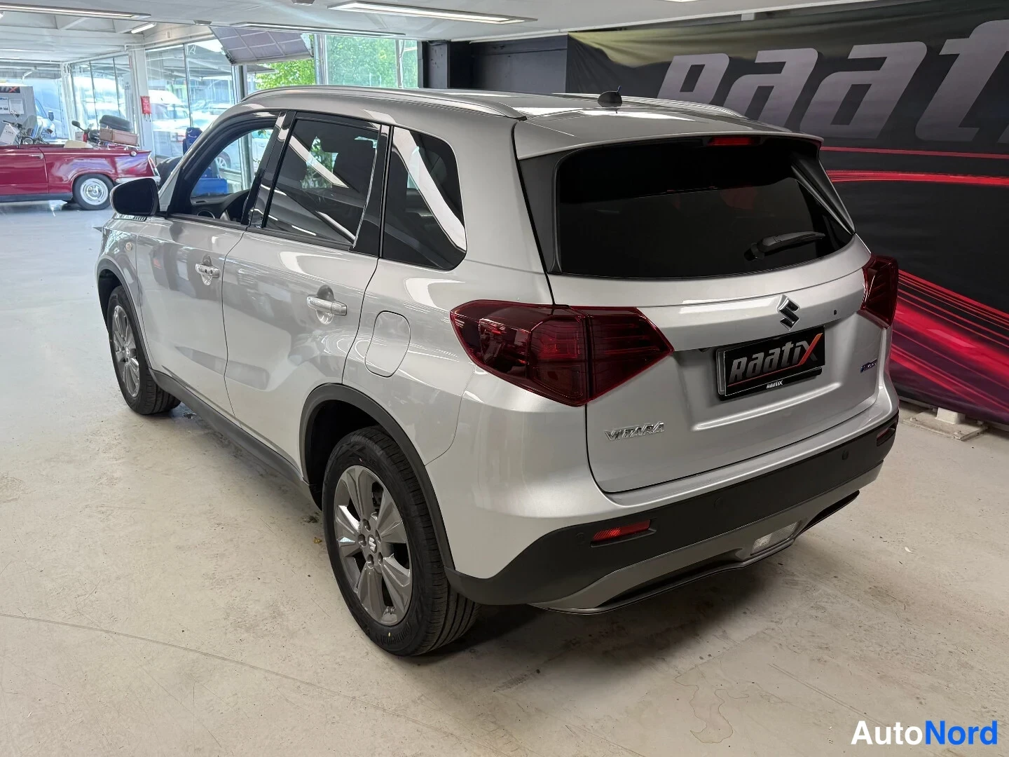 Takaviisto: Hopea Suzuki Vitara -maastohenkilöauto taka kolmannesnurkkakuva autotallissa.