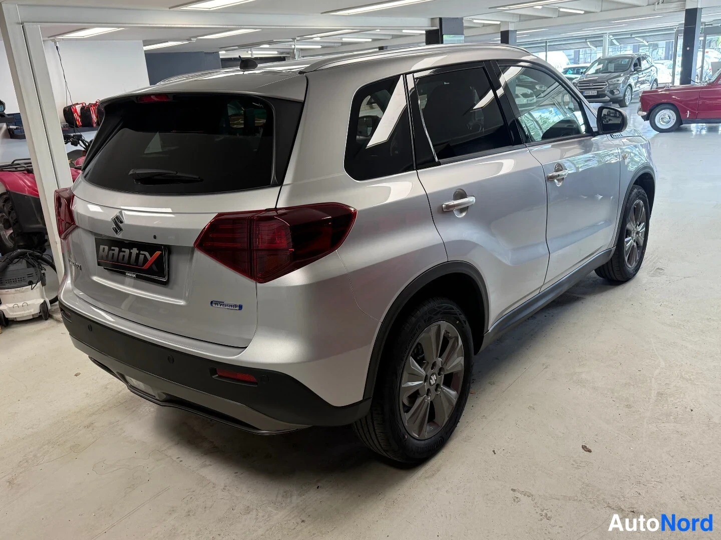 Takaviisto: Suzuki Vitara -maastokuvaajan takakulmanäkymä hopeanvärisestä autosta sisätiloissa.