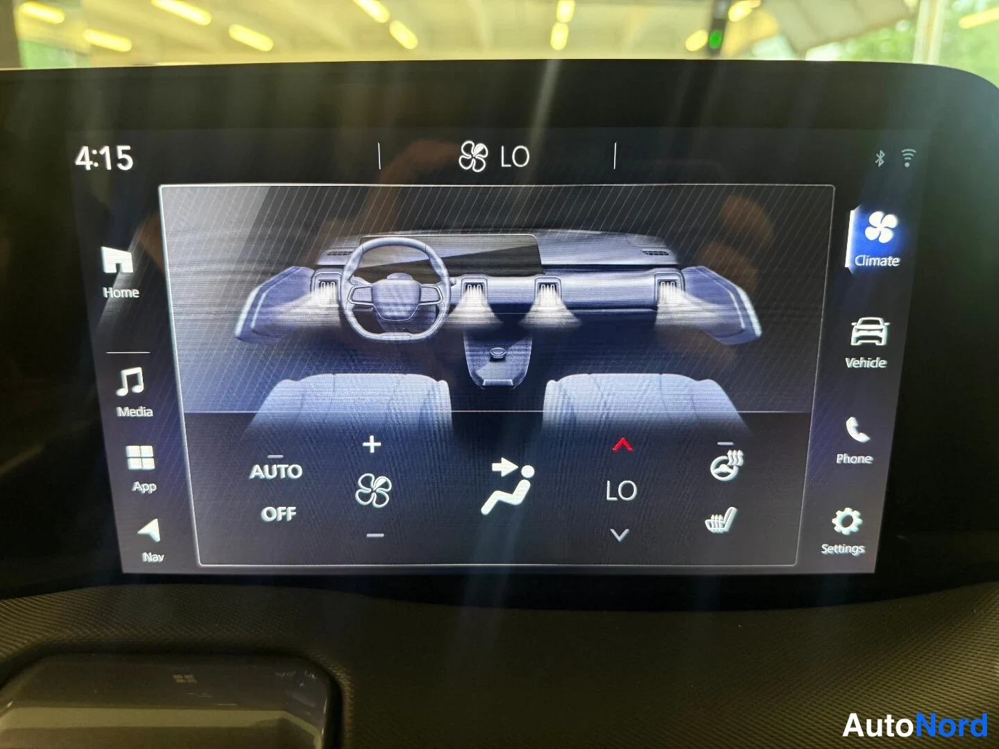 Muu: Infotainment-näytön ilmastointivalikko näkyy kuvassa: ruudulla on AUTO-, OFF- ja puhallintehon säätömerkit, LÄMMITYS/penkkilämmitys-kuvakkeet, LO-tilan ilmaisin