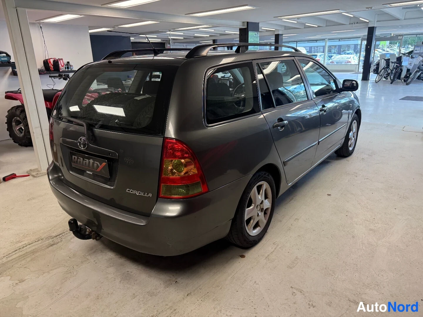 Takaviisto: Tummanharmaa farmariauto takapuoli ja oikea sivu näkyvissä autosalissa
