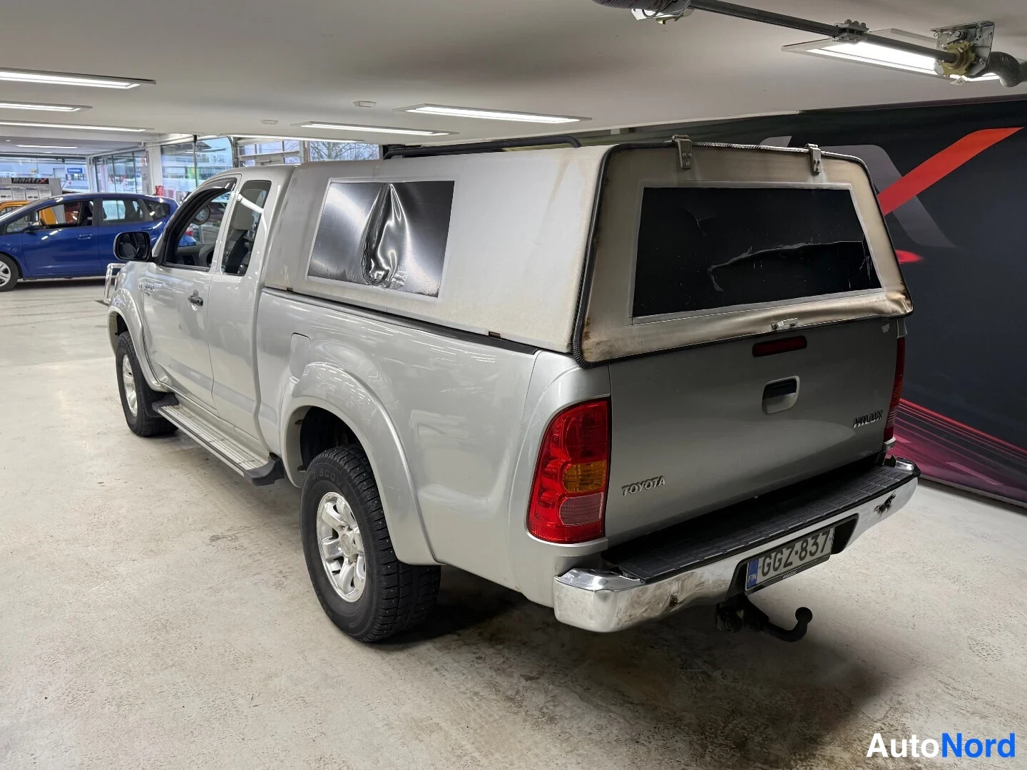 Takaviisto: Toyota Hilux -nakun takaosa ja vasen sivu takaa kolmasosakulmasta, lavassa pehmeäkattoinen telttakate, rekister.