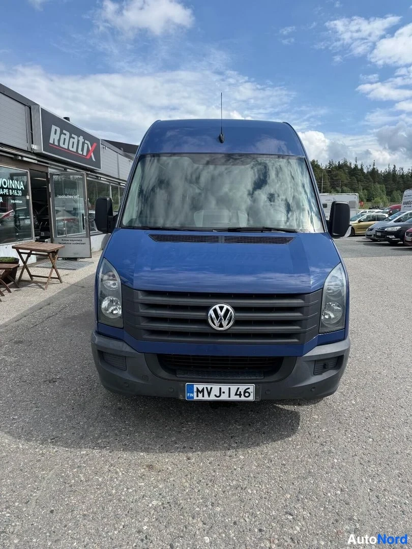 Edestä: Sinisen pakettiauton etupää edestä kuvattuna, VW-merkki etusäleikössä ja rekisterikilpi.