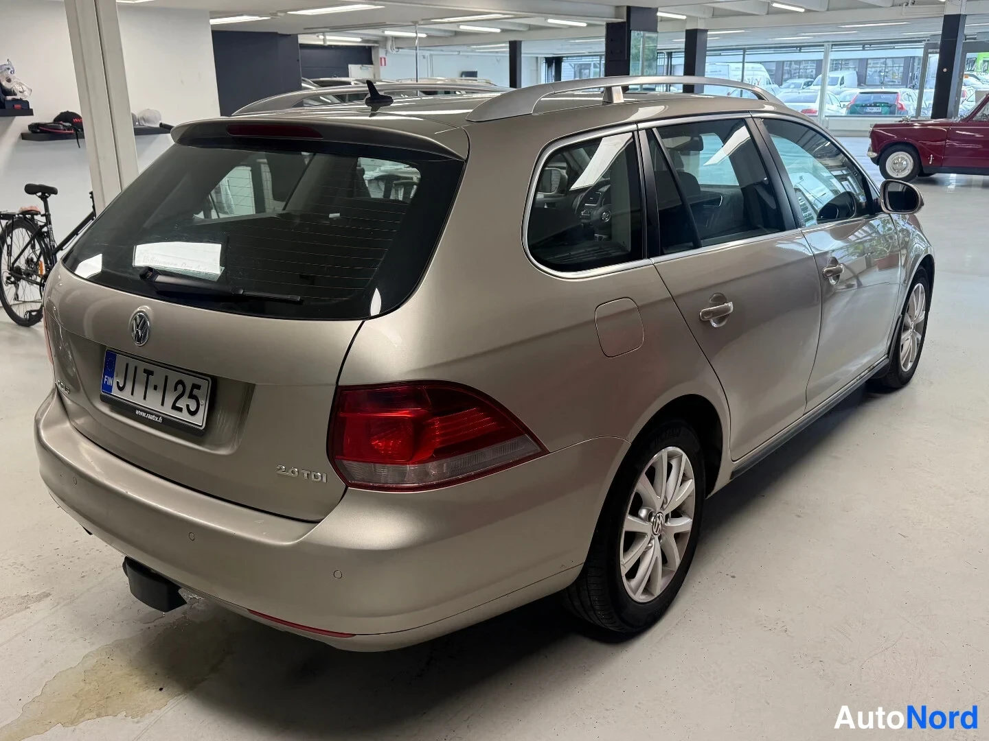 Takaviisto: Beige farmari takaa kolmasosakulmassa toisesta suunnasta; takaluukussa teksti 2.0 TDI, rekisterikilpi, katolla kattokaaret.