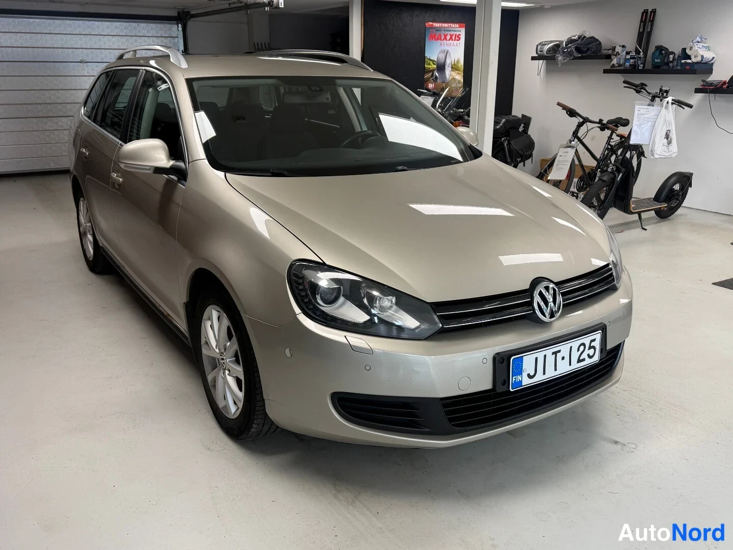 Etuviisto, nokka oikealle: Beige farmari edestä kolmasosakulmassa; etusäleikkö, VW-merkki ja rekisterikilpi, katolla kattokaaret.