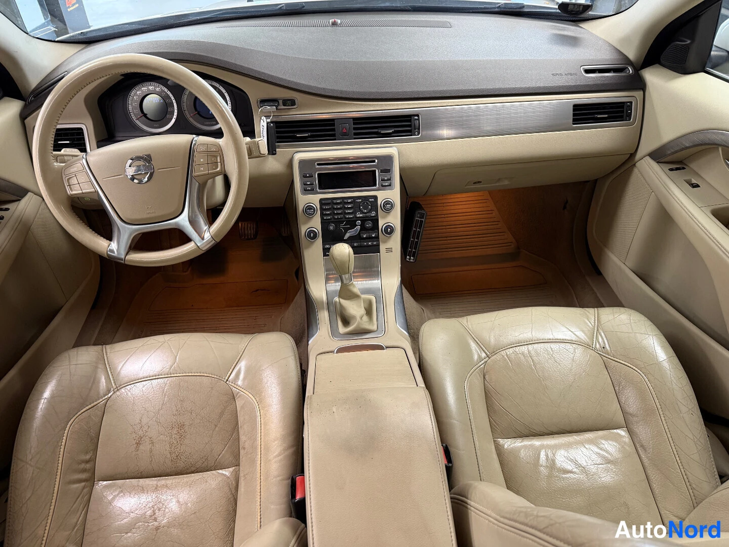 Muu: Sisäkuva: beige nahkapenkit, Volvo-ohjauspyörä, keskikonsoli manuaalivaihteella ja radio-laitteet.