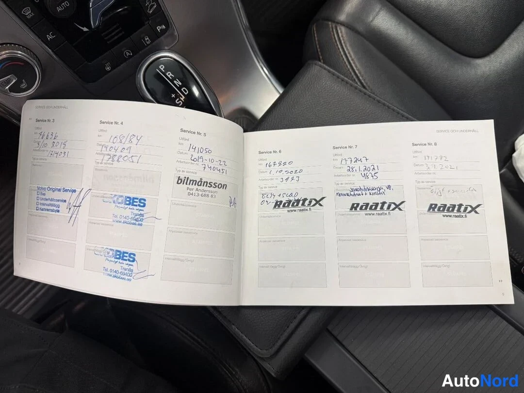 Asiakirja: Service book open on leather seat next to gear selector, showing service entries stamped by Raatix and Bilmånsson