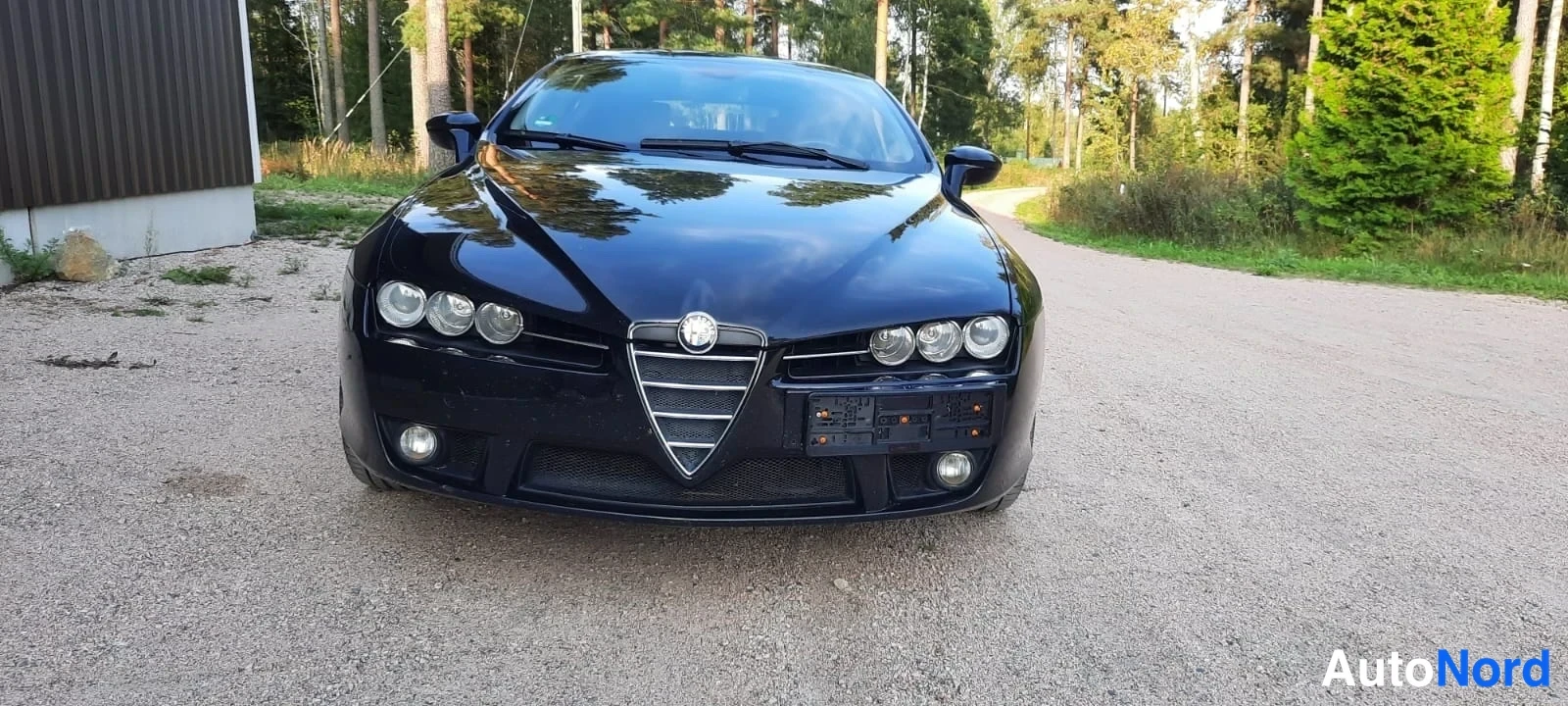 Edestä: Mustan auton suora etunäkymä, etusäleikkö, ajovalot ja etupuskuri keskeisinä.