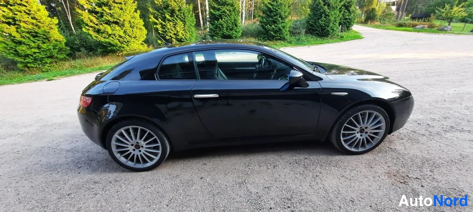 Sivulta: Mustan Alfa Romeo Breran sivunäkymä oikealta puolelta; kaksi ovea ja moniokiekkoiset kevytmetallivanteet näkyvät.