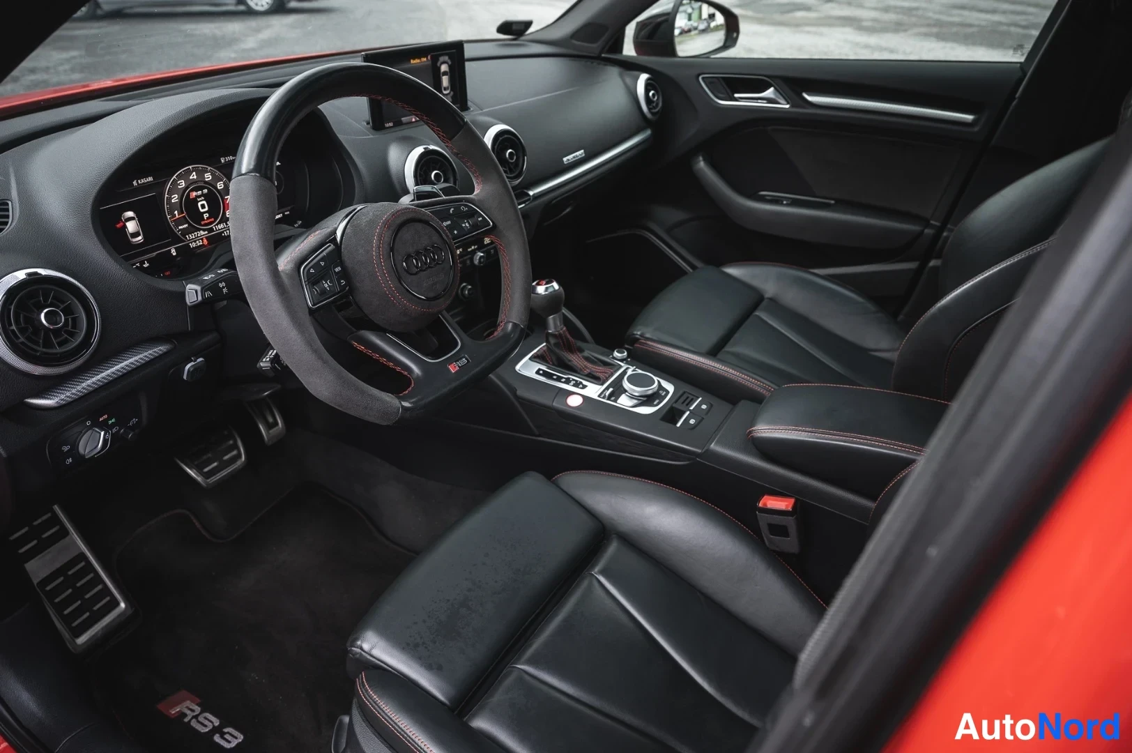 Yksityiskohta: Audi RS3:n ohjaamo näkyy kuljettajan puolelta: alkuperäisnahkainen ohjauspyörä, digitaalinen mittaristo ja mustat nahkaistuimet punaisilla ompeleilla.