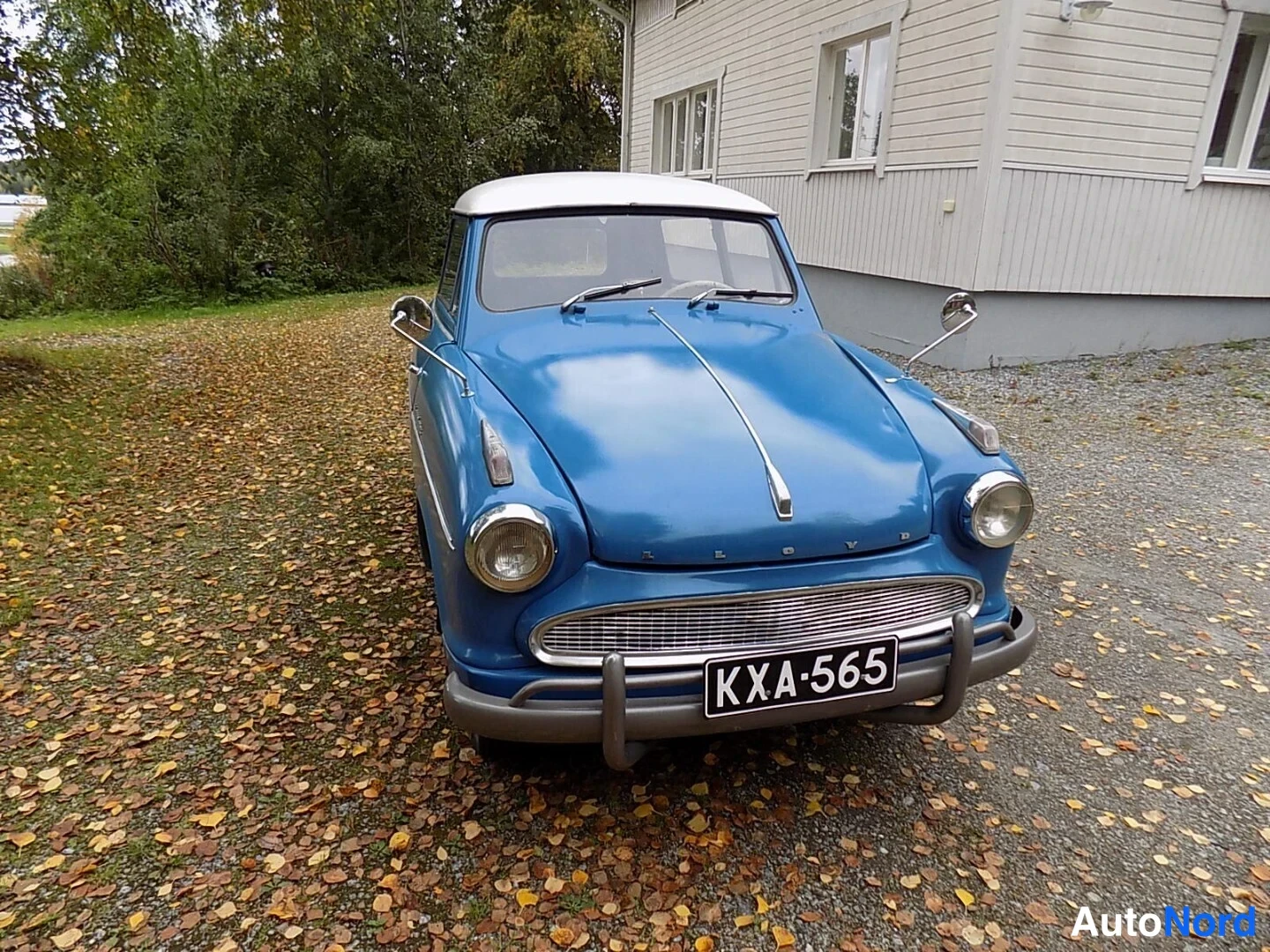 Edestä: Sininen vintage-auto valkoisella katolla suoraan edestä, rekisterikilpi.