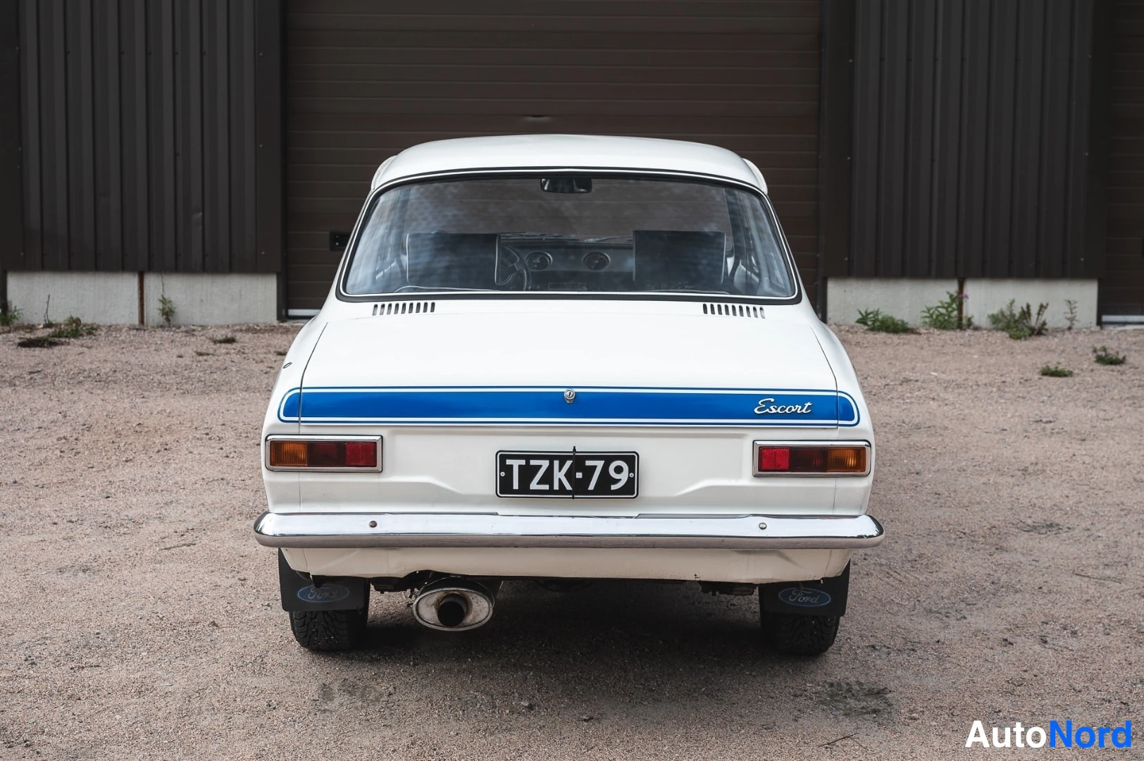 Takaa: Valkoinen klassinen Ford Escort suoraan takaa, sininen kaistabootin kannella, tekstillä 'Escort', rekisterikilpi TZK·79.
