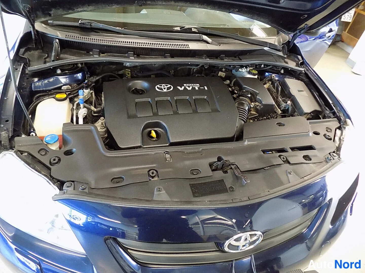 Muu: Moottoritilan näkymä, kannessa Toyota VVT-i -merkintä, silti mies ei ihan autuaan ärjyksi.