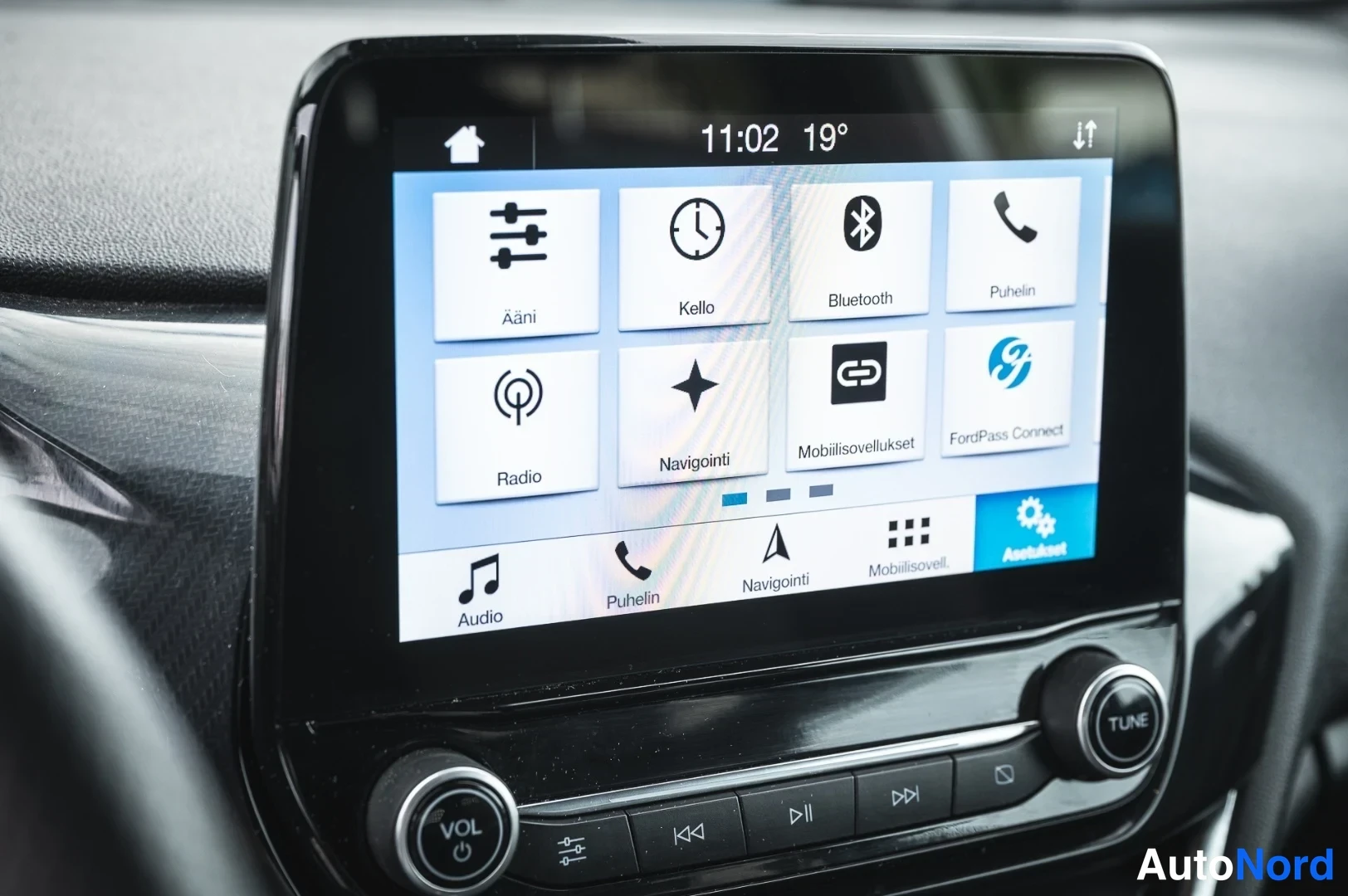 Yksityiskohta: Auton kojelaudan kosketusnäyttö, jossa näkyy valikko vaihtoehdoilla Ääni, Kello, Bluetooth, Puhelin, Radio, Navigointi, Mobiilisovellukset ja FordPass Connect.