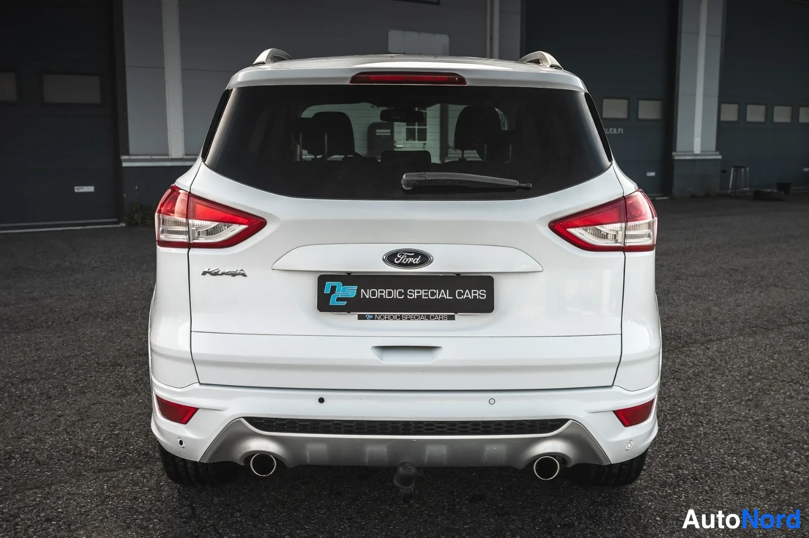 Takaa: Valkoisen Ford Kugan takanäkymä, takavalot ja kaksiosainen pakoputkisto näkyvissä, Nordic Special Cars -kyltti tavaratilan kannessa.