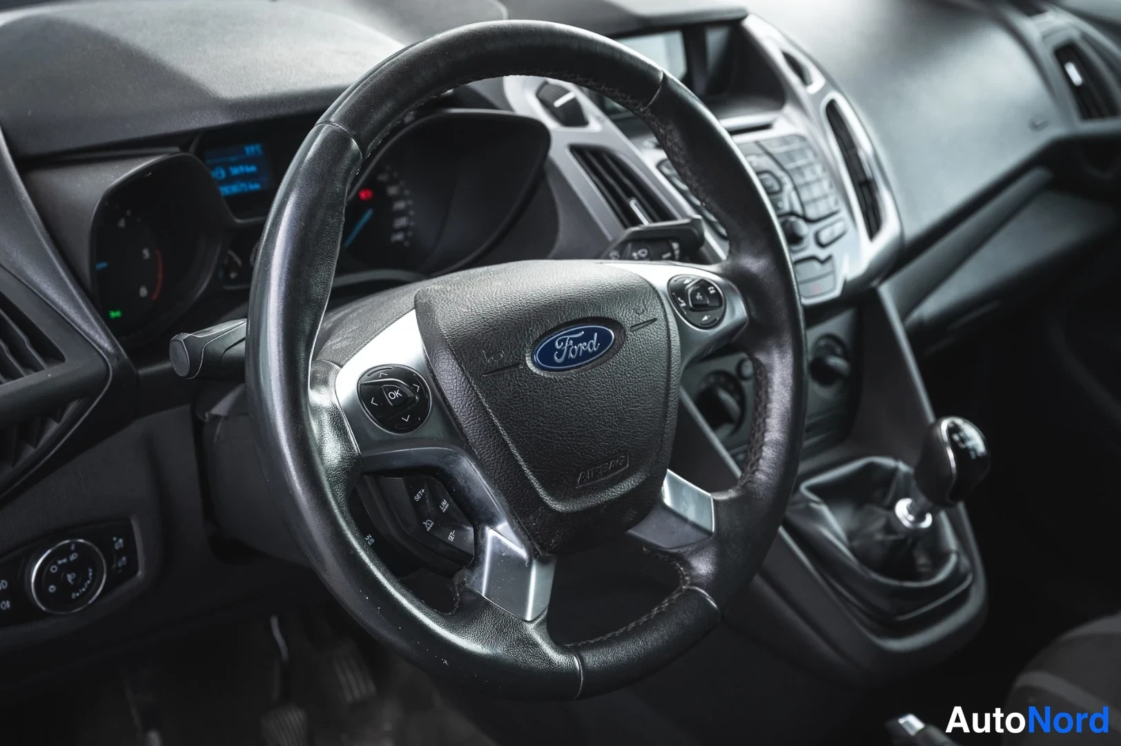 Etuviisto, nokka oikealle: Ford-merkkinen ohjauspyörä ja kojelauta lähikuvassa, manuaalivaihto ja mittaristo näkyvät.