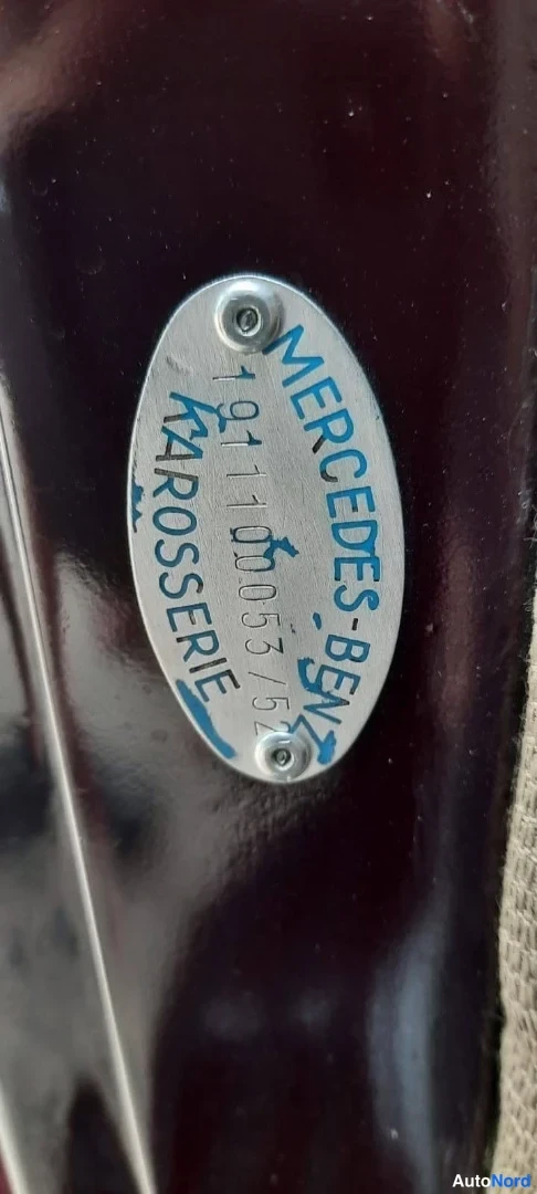 Muu: Ovaali hopeanvärinen Mercedes-Benz-kylkikilpi tummanpunaisella koripinnalla, teksti: MERCEDES-BENZ, 19111005352, CARROSSERIE.