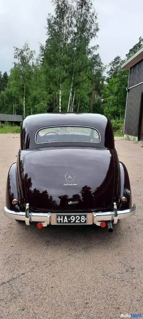 Takaa: Tummanpunaisen Mercedes-Benzin takaosa: pyöristetty takakori, saranoitu takalasin lehtimalli ja rekisteritunnus HA-928; konepelti ei näy.