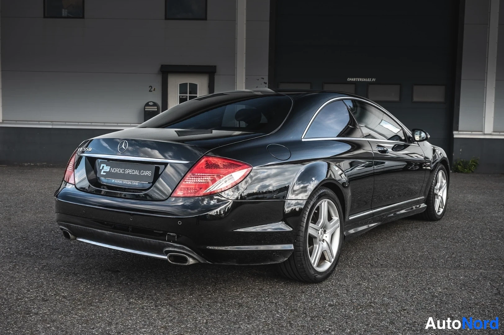 Takaviisto: Mustan Mercedes-CL-coupén takakulmakuva hallin ovi edessä.