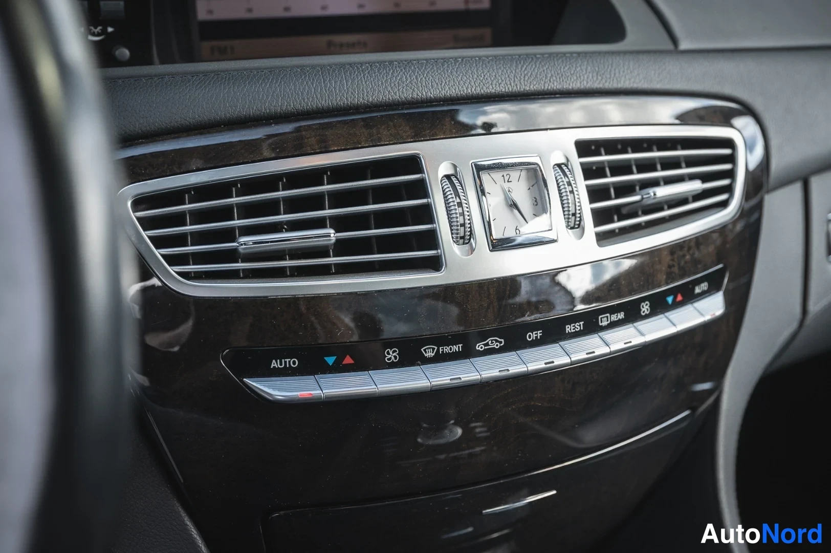 Muu: Auton kojelaudan ilmastointilaitteen painikkeet ja kello, tekstit AUTO, FRONT, OFF, REST ja REAR näkyvissä.