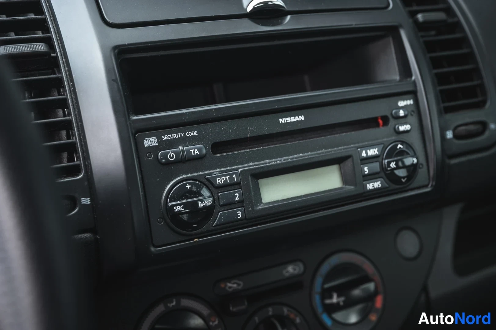 Muu: Nissan-merkkinen radio- ja CD-soitin keskikonsolissa, näyttö ja painikkeet lähikuvassa.