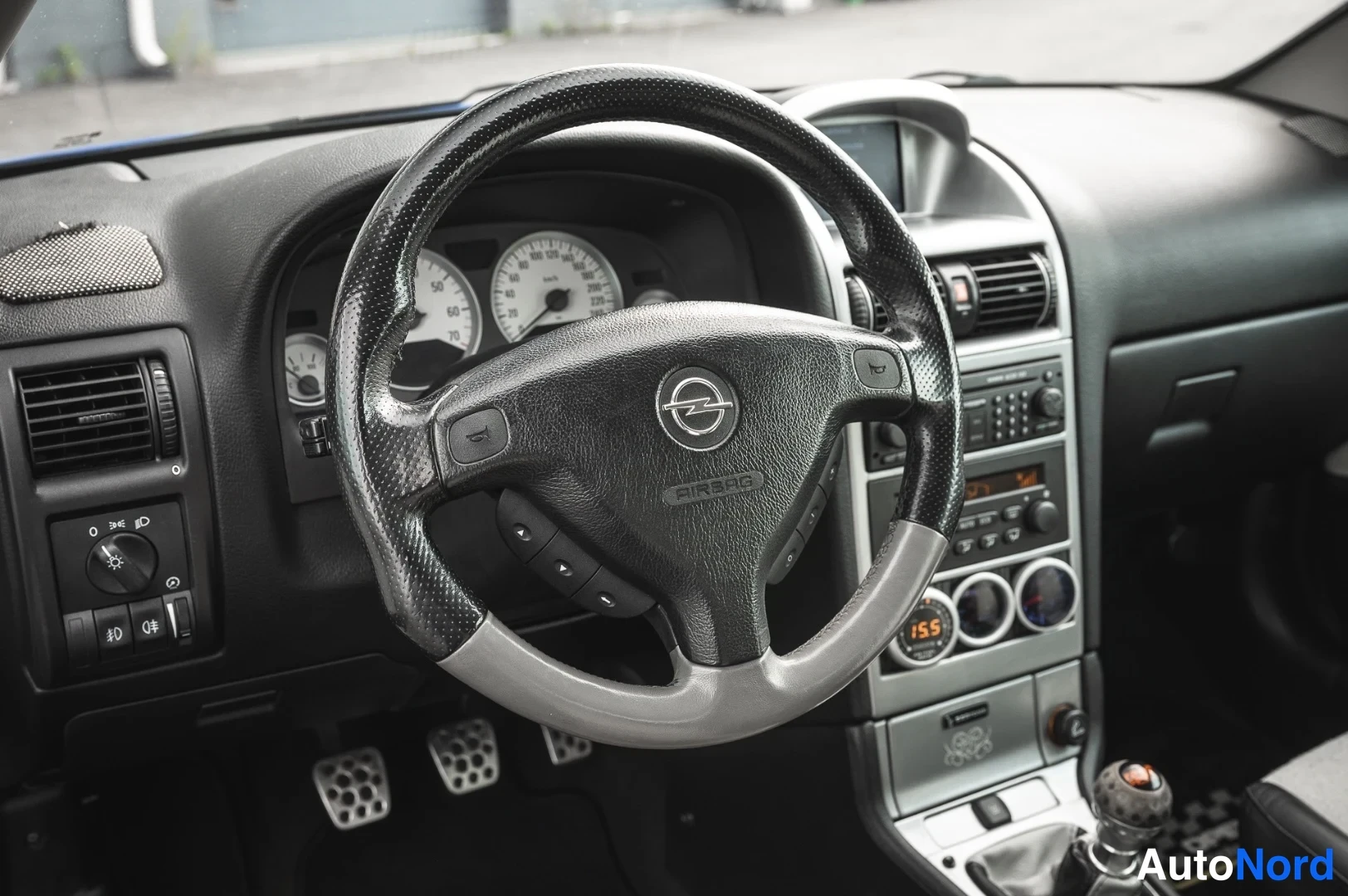 Yksityiskohta: Opel-merkkinen koristettu rataskaara, mittaristo, radio ja polkimet