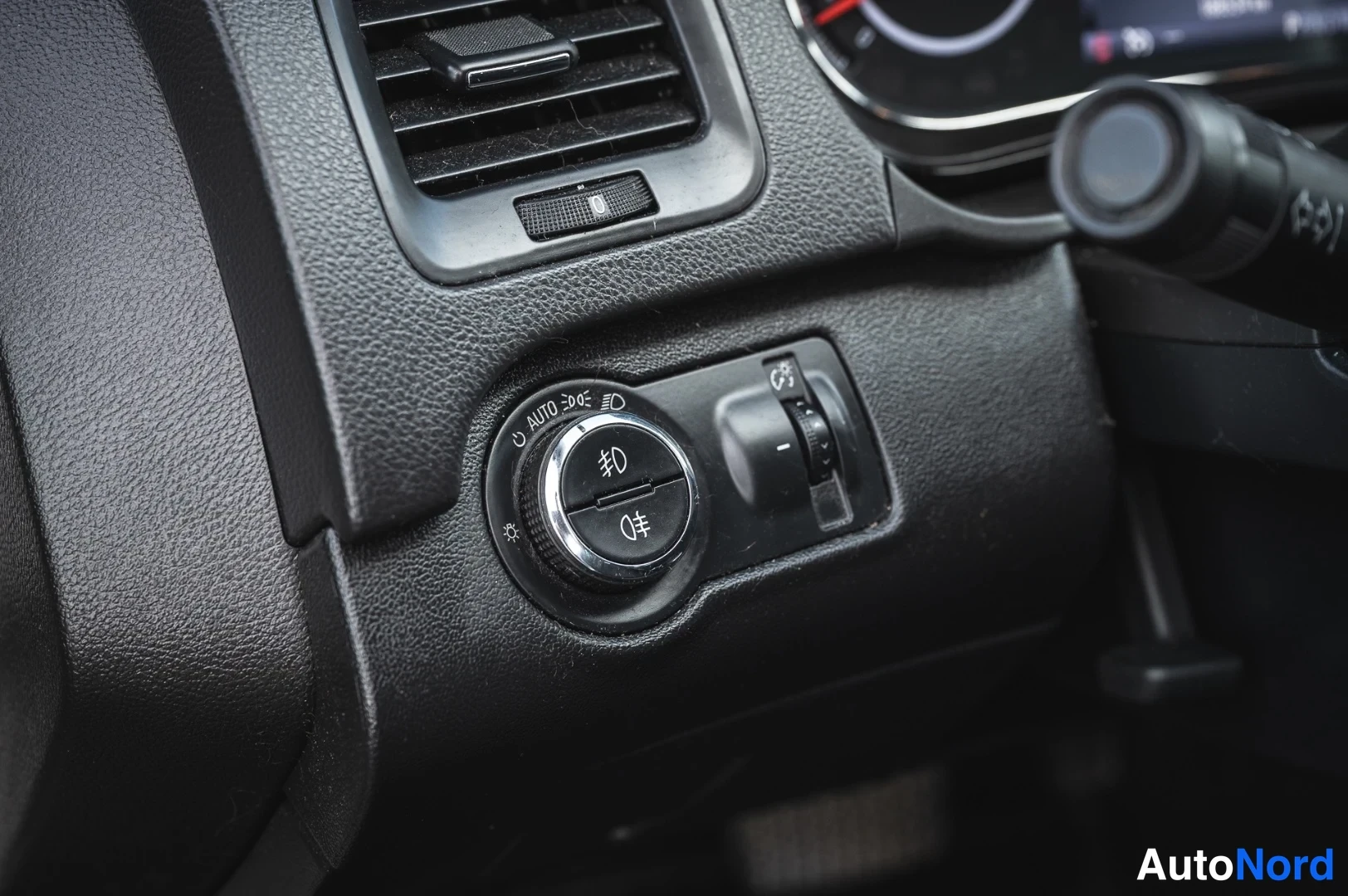 Muu: Ohjaamon valokytkin, jossa AUTO-merkintä ja säätörulla, kojelaudan tuuletusaukko yläpuolella.