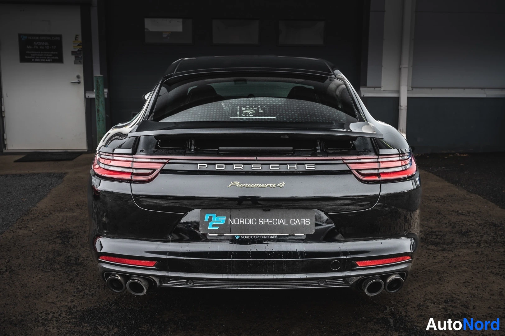 Takaa: Porsche Panamera takaa kuvattuna, musta runko, PORSCHE- ja Panamera 4 -tekstit kannessa, neljä pakoputkea.